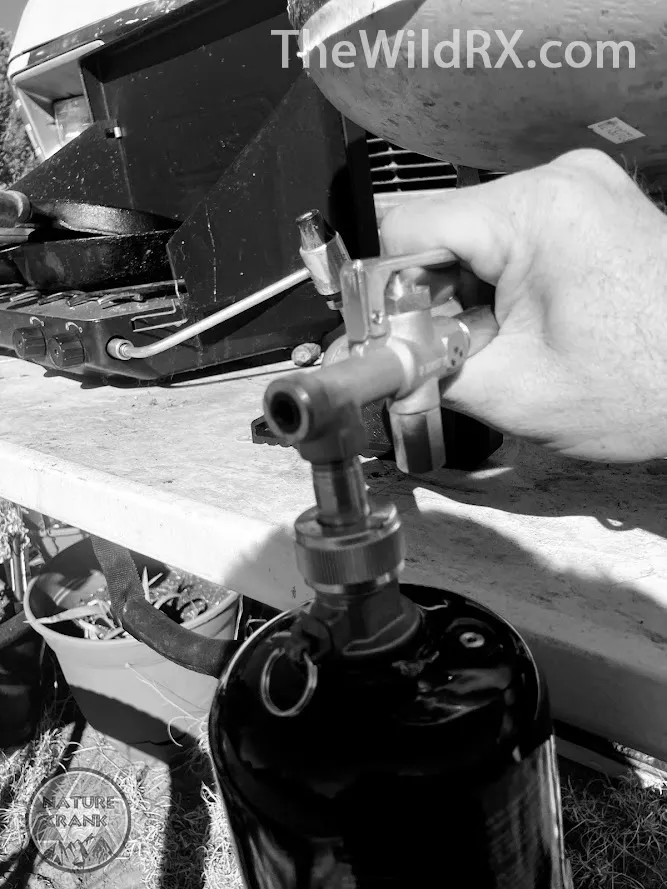 The complete Mr. Heater Fuel Keg refill kit setup showing a 1lb bottle connected to an inverted 20lb propane tank using the official adapter and stabilizing feet.