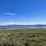 panoramic landscape view of Blackfoot Reservoir Lake in Idaho, showing the blue water and surrounding hills from the Blackfoot Mountain Range