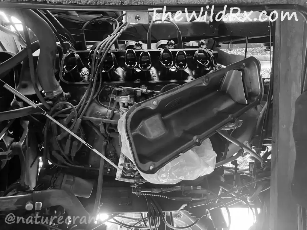 A person working on the engine of a vintage RV to replace a leaking valve cover gasket.