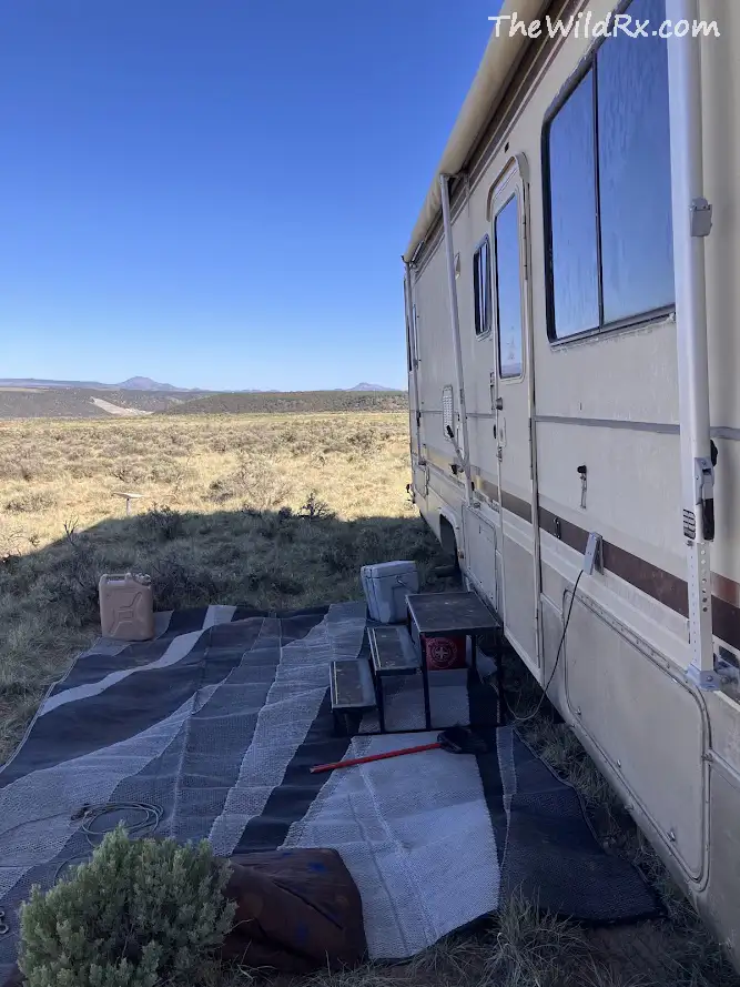 A side-view of a parked RV on open public BLM land in the Utah desert with mountains in the distance.