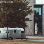 Modern motorhome parked next to a suburban house -- RV living vs homeownership costs.