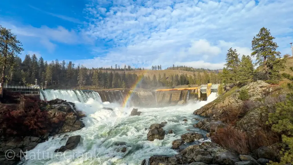 A brilliant rainbow forms in the mist rising from the roaring spillway waterfalls of the Little Falls Dam on the Spokane River near Ford, Washington.