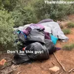 A pile of black trash bags and abandoned camping gear left behind in a natural desert environment with brush and red dirt.