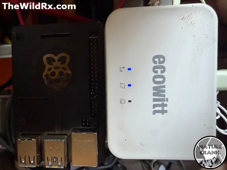 A Raspberry Pi in a black case next to a white Ecowitt weather station gateway used for off-grid RV monitoring.